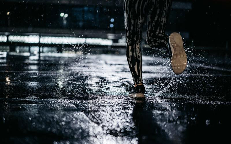 A woman running in the rain at night